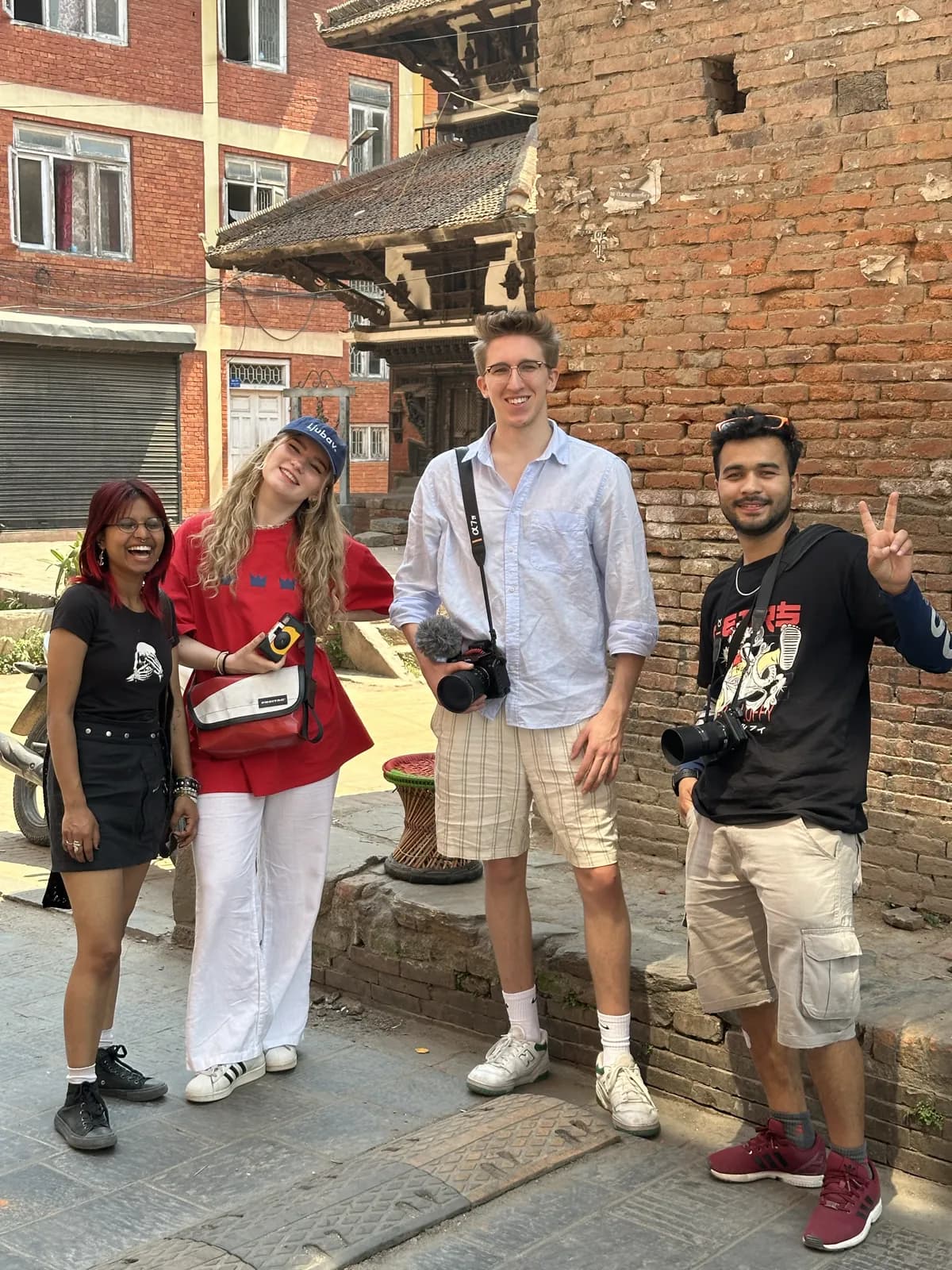 Das Team vor Ort in einer Straße in Kathmandu, Kameras in der Hand, im Hintergrund ein Tempel aus Backstein